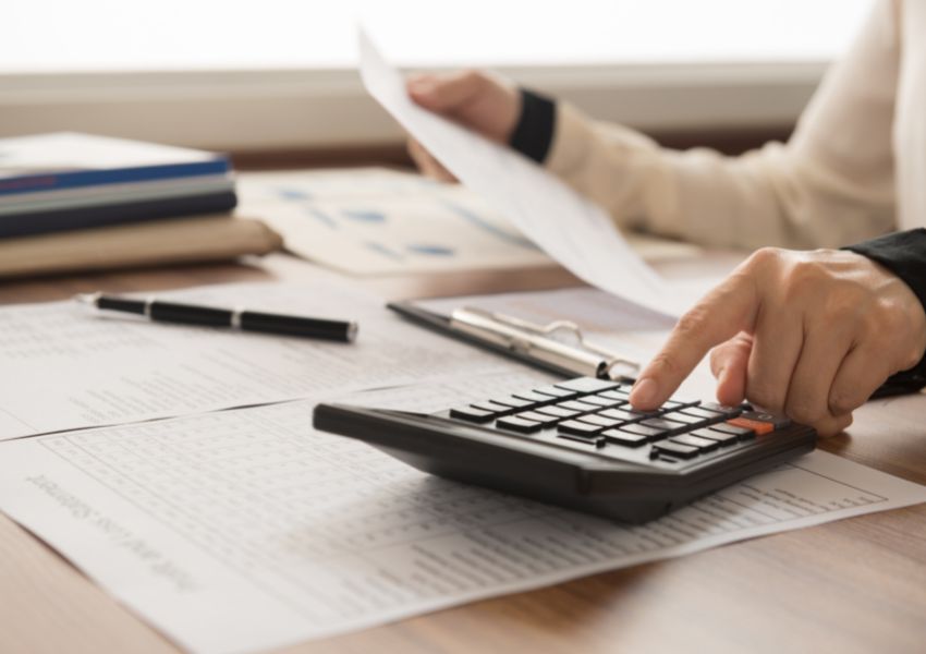 A property manager completes accounting tasks at a desk, inputting numbers into a calculator.
