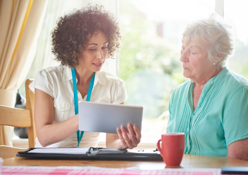 A property manager with mid length curly hair asks a prospective tenant essential screening questions that they read from a clipboard.