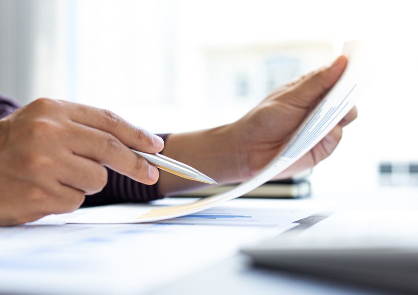 A landlord's hands are pictured, holding a silver pen and figures relating to their investment's performance.