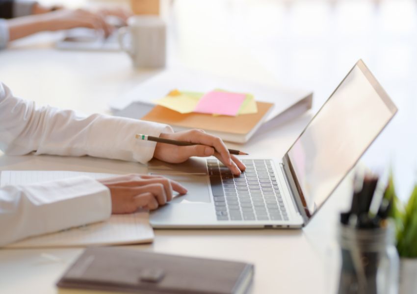 A landlord's hands touch the keyboard of a silver laptop at a desk, as they examine their marketing strategy.